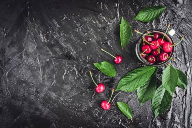 Kiraz koyu ahşap zemin üzerine yeşil yaprakları ile beyaz kupa.