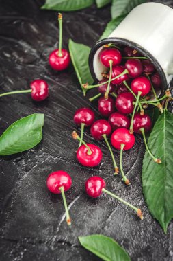 Kiraz koyu ahşap zemin üzerine yeşil yaprakları ile beyaz kupa.