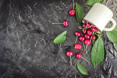 Kiraz koyu ahşap zemin üzerine yeşil yaprakları ile beyaz kupa.