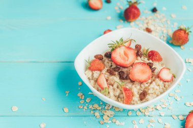 Taze çilek ve mavi ahşap zemin üzerine kuru üzüm yulaf ezmesi. Sağlıklı ve diyet yiyecek. Yaz kahvaltı.