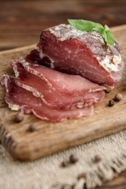 Köy ahşap arka planda kurutulmuş domuz eti dilimleri. Kurutulmuş domuz jambonlu ve otlu salam..