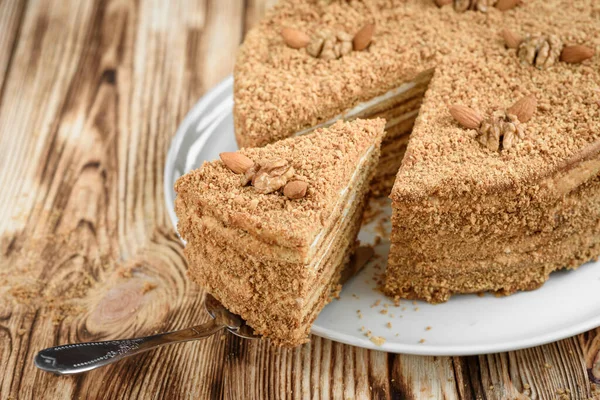 Hausgemachter Geschichteter Honigkuchen Mit Nüssen Und Kuchenstück Auf Weißem Teller — Stockfoto