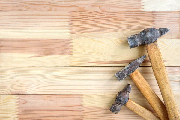 Old hammers on wooden background.