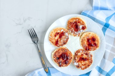 Beyaz arka planda ekşi kremalı ve çilek reçelli süzme peynir krepleri, kahvaltı ya da öğle yemeği