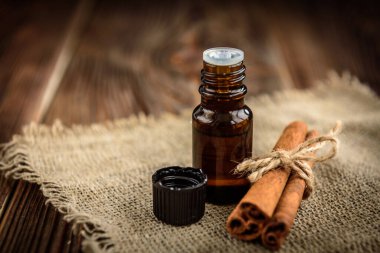 Koyu ahşap arka planda bir şişe tarçın yağı. Spa malzemeleri.