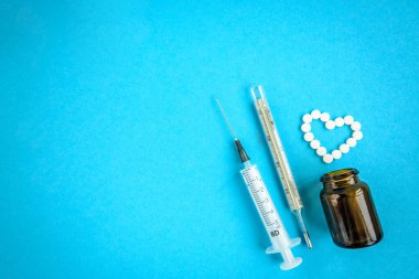 Mavi arka planda izole edilmiş kalp şeklinde beyaz tabletler. 