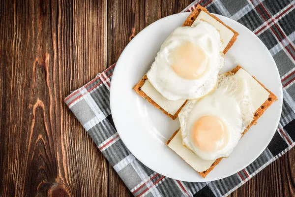 Healthy sandwiches with soft cheese and egg on crisp rye bread on dark wooden background.