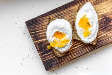 Sağlıklı yumurtalı sandviç, beyaz arka planda çavdar ekmeği ve tahta kesme tahtası..
