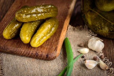 Tahta bir masada salatalık turşusu ve sarımsak ve turşu kavanozu..