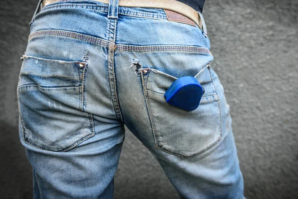 Eski, kirli ve yırtık kot pantolon. Kotun cebinde inşaat bandı olan bir işçi..