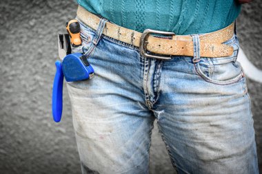 Eski, kirli ve yırtık kot pantolon. Kotun cebinde inşaat bandı olan bir işçi..