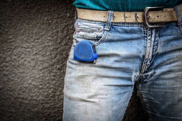 Construction old dirty and ripped jean. Worker with a construction measuring tape in a jeans pocket.