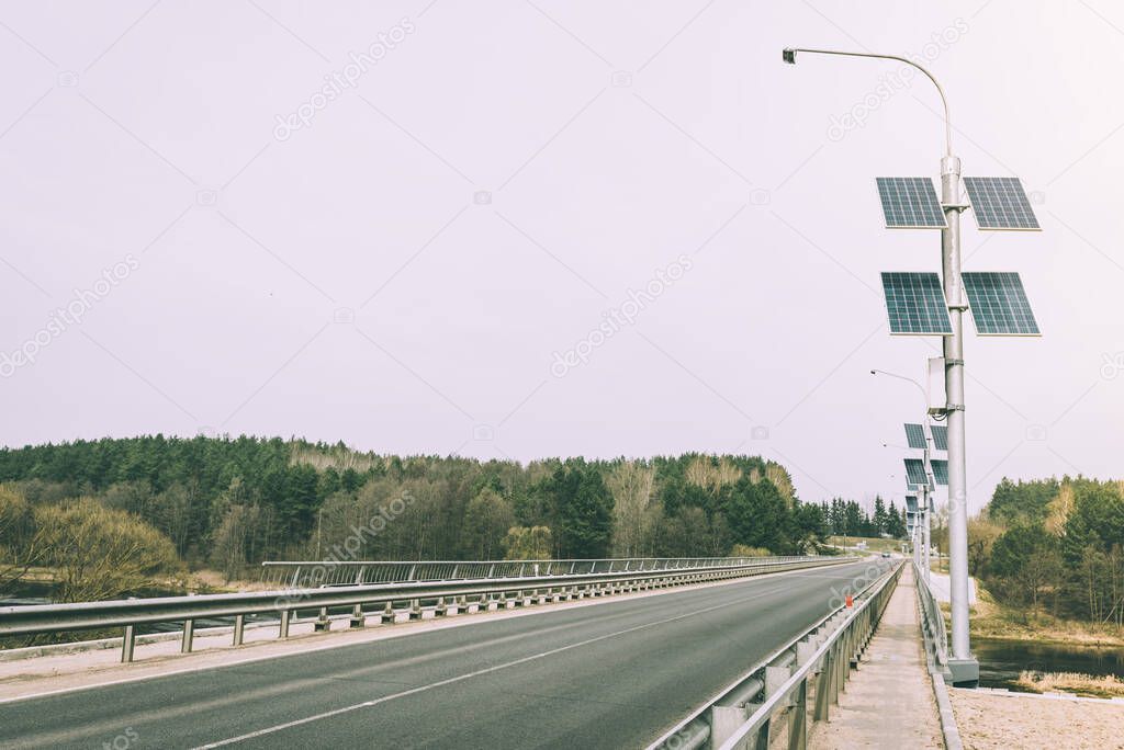 Street lamp poles powered by solar energy. Solar panels on electric pole for lighting on the road in the city on the bridge. Use of solar energy.