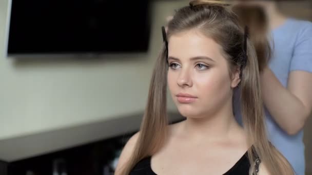Kadeřník je poslední fáze vytváření účes pro roztomilá dívka. Profesionální kadeřník kadeřník dělá účes pro evropské roztomilé děvčátko v domě. — Stock video