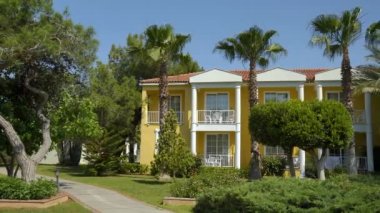 Uzun palmiye ağaçları sarı binanın karşı büyümek. Panorama soldan sağa.