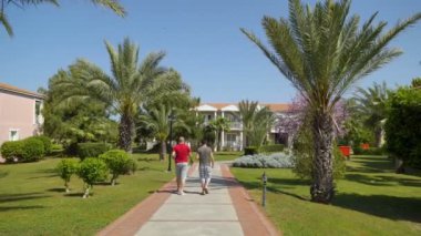 Bahar, iki adam geçip, palmiye ağaçları ile güzel yeşil sokak