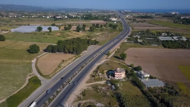 Een zicht van boven op de weg waarop auto's zijn reizen. Luchtfoto schieten van de weg tussen de velden. De auto's zijn bewegende langs de weg. — Stockvideo