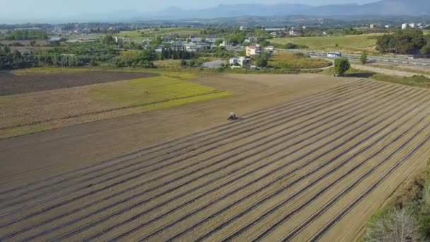 Mezőgazdasági traktor a barna mezőn. A drone körül egy traktor, vidéken a területén dolgozó repül. Videóklipek