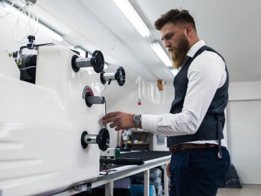 Genç terzi yeni elbiseler üzerinde çalışıyor.