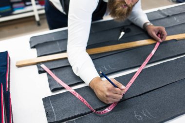 Genç terzi yeni elbiseler üzerinde çalışıyor.