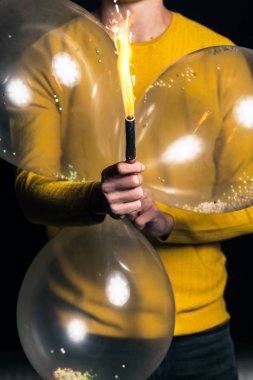 Sarı kazaklı genç adam tutun balonlar ve ışıltı