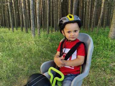 Bir bisiklet çocuk koltuğunda oturan bir kask sevimli bebek çocuk. O bir yolculuk ile mutlu