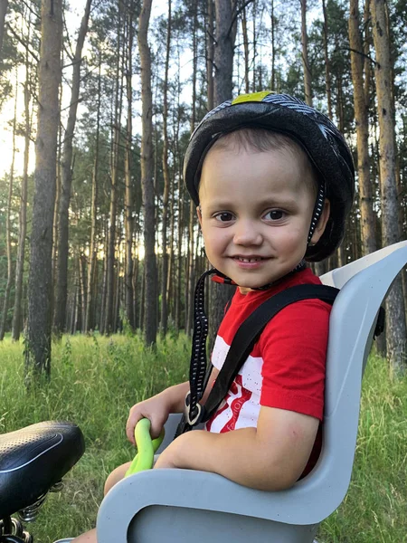 Bir bisiklet çocuk koltuğunda oturan bir kask sevimli bebek çocuk. O bir yolculuk ile mutlu