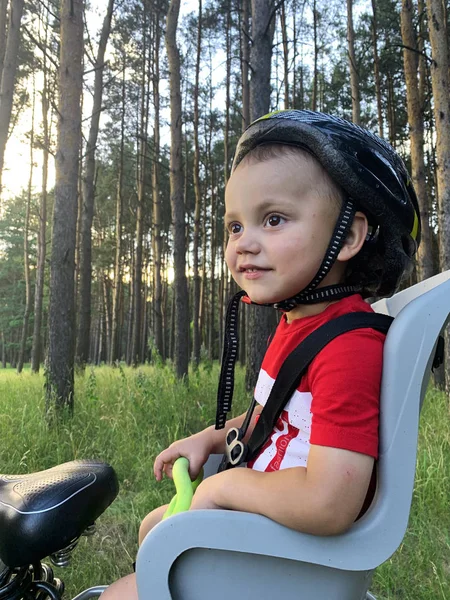 Bir bisiklet çocuk koltuğunda oturan bir kask sevimli bebek çocuk. O bir yolculuk ile mutlu
