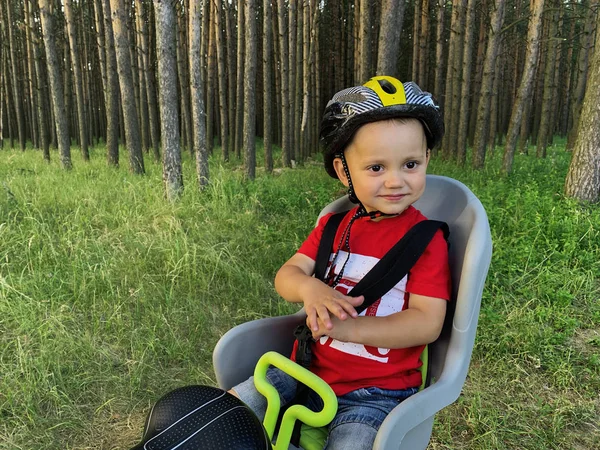 Bir bisiklet çocuk koltuğunda oturan bir kask sevimli bebek çocuk. O bir yolculuk ile mutlu
