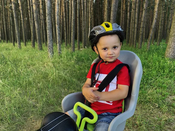 Bir bisiklet çocuk koltuğunda oturan bir kask sevimli bebek çocuk. O bir yolculuk ile mutlu