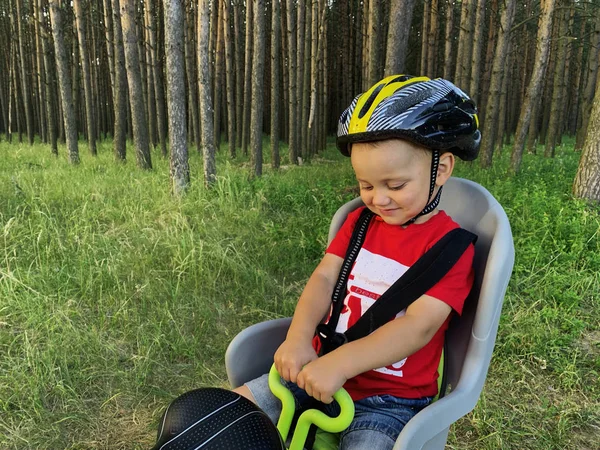 Bir bisiklet çocuk koltuğunda oturan bir kask sevimli bebek çocuk. O bir yolculuk ile mutlu