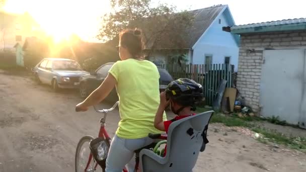 Moeder Rijdt Met Een Kind Een Baby Fietszitje Bij Zonsondergang — Stockvideo