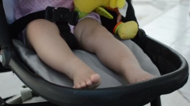 Bebek arabası içinde oynarken bebek bacakları yakın çekim.