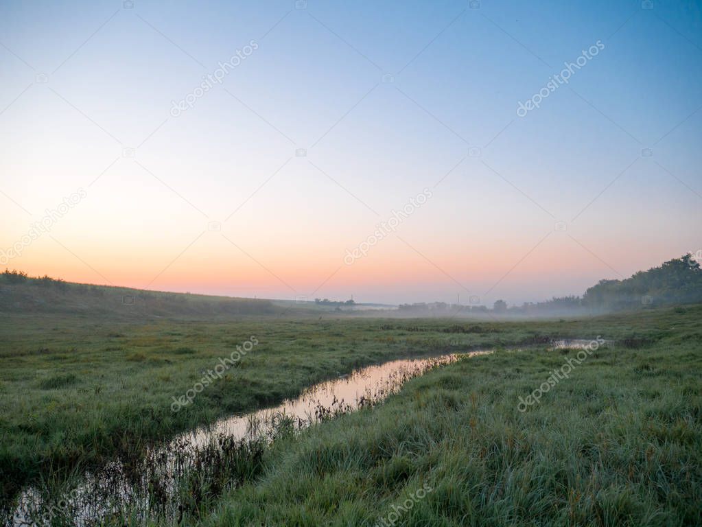 Morning misty landscape in a meadow stream