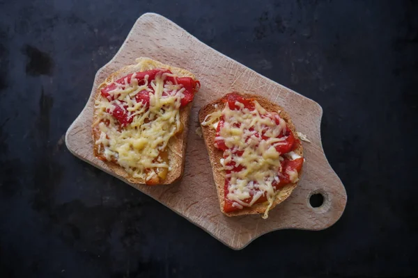 kruton biber ve karanlık bir arka plan üzerinde ahşap bir tahta üzerinde peynir ile