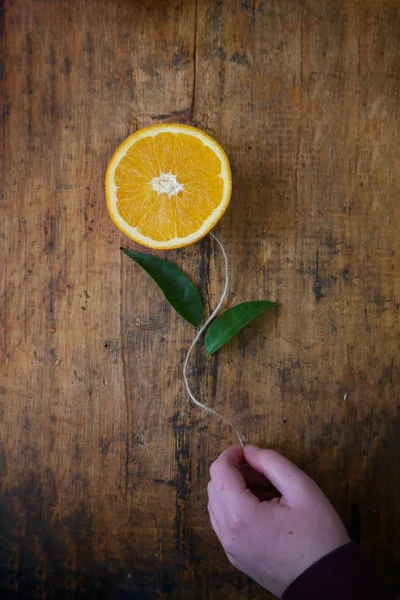 El tutar çiçek, çiçek olarak portakal dilim, ipek iplik olarak kök ve ahşap zemin üzerine yeşil yaprakları