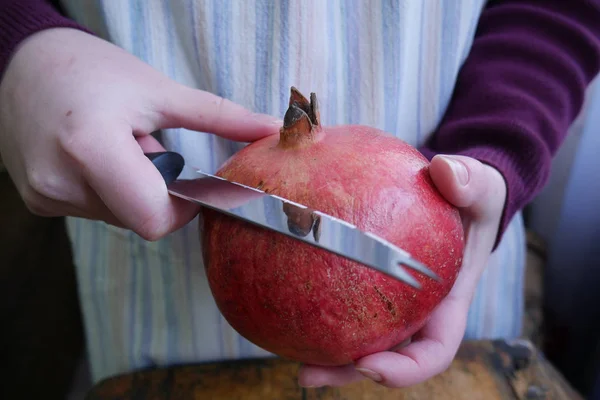 Man cuts a ripe pomegranate with a knif — Stock Photo, Image