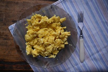 Omlet ve yanında bir çatal zemin ahşap ve kumaş üzerine bir tabak içinde