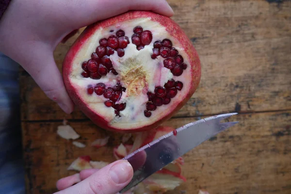 adam olgun nar ahşap arka plan üzerinde bir bıçakla keser