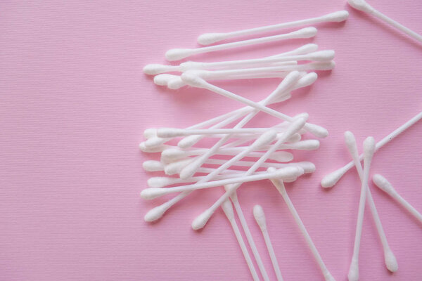 white plastic cotton buds on a pink background