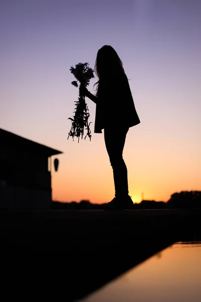 Κορίτσι σιλουέτα με ένα μπουκέτο λουλούδια στο ηλιοβασίλεμα, η έννοια της αγάπης — Φωτογραφία Αρχείου