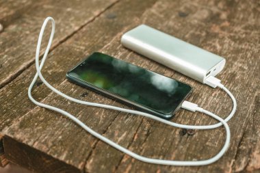 Tahta arka planda elektrik bankası olan boş batarya akıllı telefonunu şarj etmek 