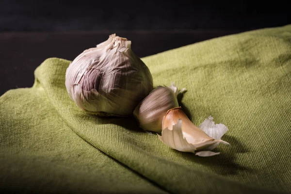 Isolated garlic on a green cloth napkin side lit giving an early morning moody atmosphere.