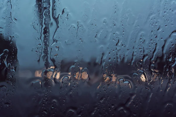 Heavy rain streaming down a windshield in rush hour traffic