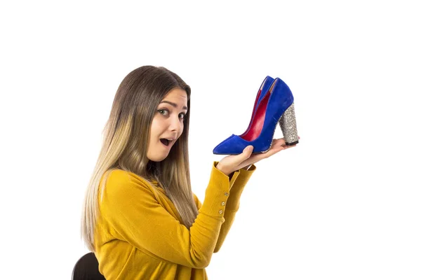 白い背景の上のかかとの高い靴のペアを保持している若い女性をびっくり — ストック写真