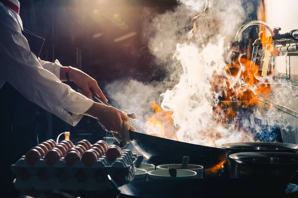 Şef tavada kızartma yapıyor.