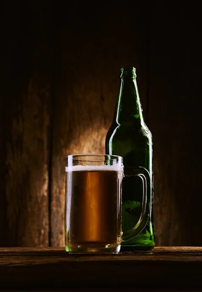Öl med flaska i mugg på träbord — Stockfoto