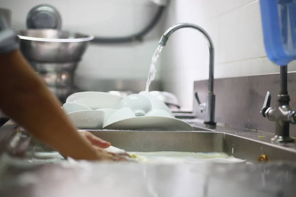 Woman washing dish on sink at restaurant
