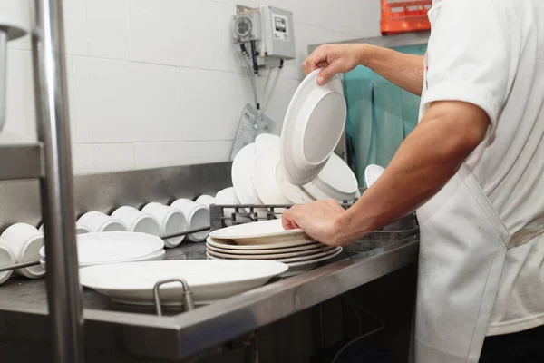 Man washing dish on sink at restaurant