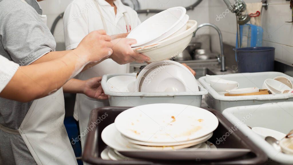 Man washing dish on sink at restaurant